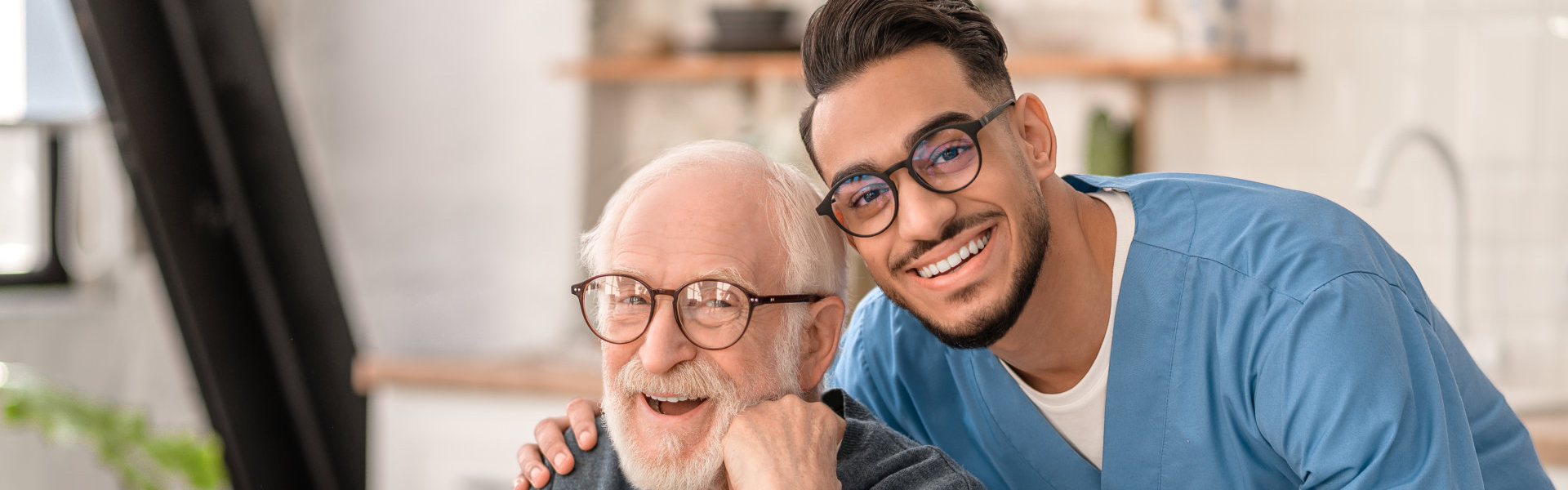 Elderly man and male caregiver smiling